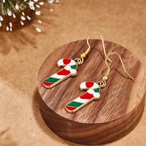 Close-up of candy cane earrings with red and green stripes on a wooden stand