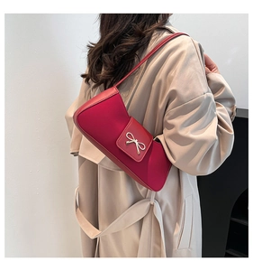 Detail shot of the red baguette bag featuring a stylish metal bow and smooth PU leather