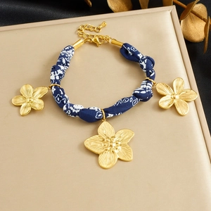Détail du bracelet en tissu bleu avec pendentifs fleurs dorées sur un support en cuir