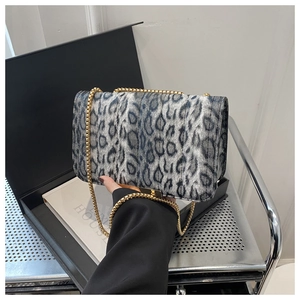 Detail of leopard print chain bag with gold buckle on luxury book background