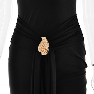 Detail of elegant waist draping and gold irregular brooch on a black fishtail dress