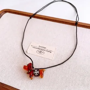 Collier avec pendentif chien en verre ambré, croix en métal et cordon noir élégant