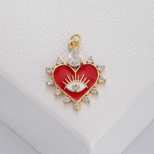 Macro shot of gold heart pendant with red enamel evil eye and sparkling zircons
