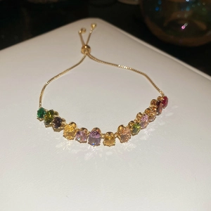 Gros plan d'un bracelet doré ajustable serti de zircons ovales multicolores