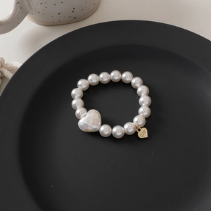Detail of pearl bracelet hair tie with faceted heart bead and gold 'CUTE' heart charm