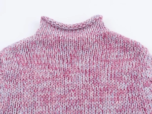 Detail of the high-neckline and textured pink gradient knit fabric on a soft sweater
