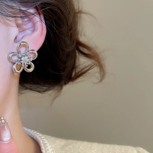 Close-up of a silver flower stud earring with sparkling zircon petals on a model