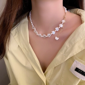 Detailed view of an irregular baroque pearl necklace with a golden heart pendant on neck