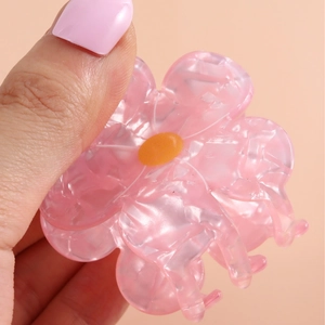 Elegant floral acetate hair claw clip in pink and yellow finish held by hand