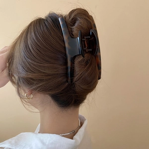 Detail of large tortoiseshell hair claw clip securing a bun on a woman's long hair