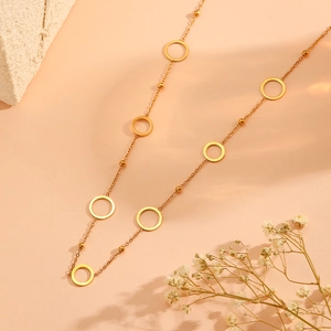 Detailed close-up of golden multi-layered hollow circle necklace on a minimalist background