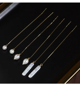 Detailed view of gold chain earrings featuring round, drop, and baroque freshwater pearls