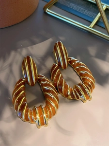 Detail of 18K gold-plated earrings with caramel enamel and spiral texture patterns