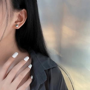 Polished silver heart-shaped stud earring worn by a model for a minimalist aesthetic