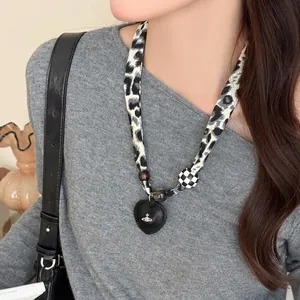 Detail of leopard print fabric cord necklace featuring a black heart orb pendant