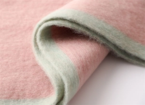 Close-up of soft cashmere-like scarf texture showing pink and light green gradient yarn