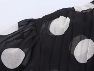 Detailed close-up of chiffon fabric featuring white polka dots and pleated shoulder design