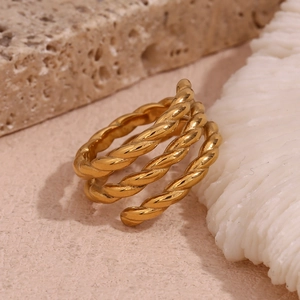 Macro shot of 18K gold plated multi-layer twisted rope ring on a textured stone surface
