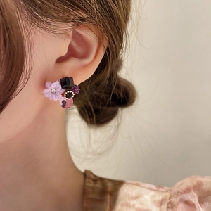 Close-up of model wearing floral cat eye stone earrings with purple crystal elements
