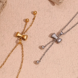 Detail of gold and silver bow necklaces with bead pendants on a textured stone surface