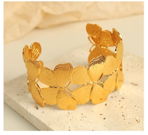 Detailed close-up of 18K gold-plated wide cuff bangle with textured butterfly design