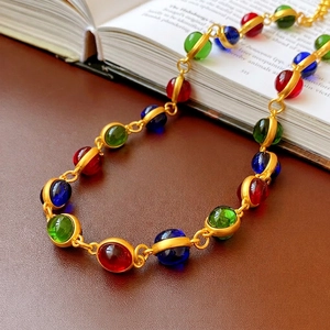 Vintage necklace with colorful beads and matte gold finish on an antique book background