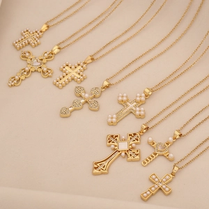 Detailed macro view of multiple golden cross pendants with pearls and small crystals