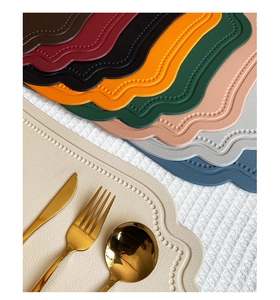 Close-up of stacked colorful faux leather placemats with scalloped beaded edges