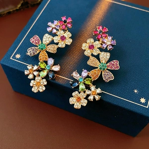 Nahaufnahme vergoldeter Blumenohrringe mit bunten Edelsteinen auf einer Schmuckschatulle
