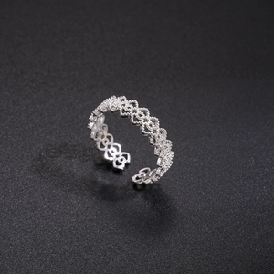 Detailed top view of silver hollow floral ring with zircon pavé on black texture
