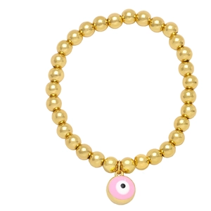 Dettaglio del ciondolo malocchio rosa su bracciale elastico a sfere dorate stile boho