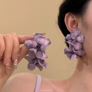 Gros plan de boucles d'oreilles fleurs en tissu violet avec pétales à couches souples