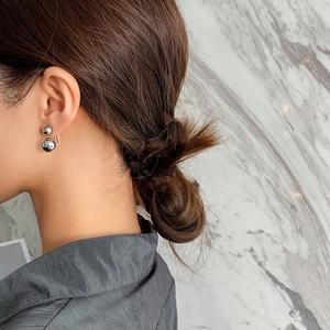Model wearing minimalist silver double metal ball earrings with a glossy geometric finish
