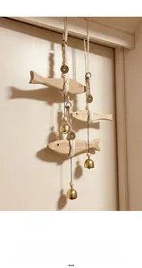 Detail eines Holzfisch-Windspiels mit Kupfermünzen und Messingglocken am Baumwollseil