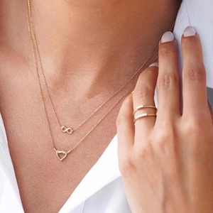 Macro shot of gold layered necklaces with infinity and heart pendants and rings