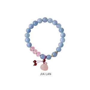 Detail of beaded bracelet with light blue stones and a pink heart-shaped pendant charm