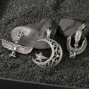 Vintage angel wings and Egyptian goddess pendants on textured black background