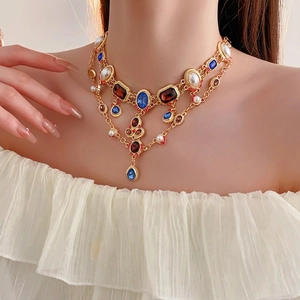 Vintage gold layered necklace with multi-colored gemstones and pearls on model