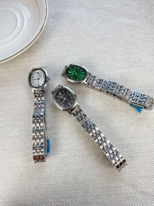 Detailed view of three small oval quartz watches with silver metal straps in three colors