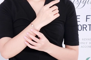 Close-up of a layered rose gold stainless steel heart bracelet on a model's wrist