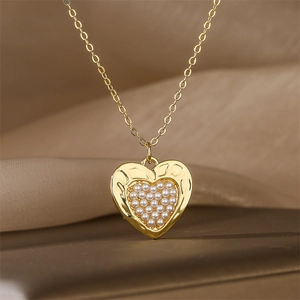 Gros plan d'un collier pendentif cœur doré avec des ornements de perles blanches