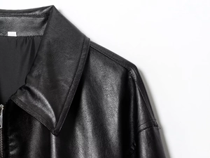 Nahaufnahme der schwarzen Fliegerjacke aus Kunstleder mit feiner Narbenstruktur und Metallreißverschluss