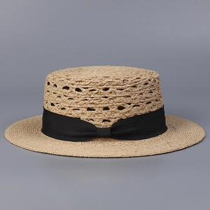 Detalle de sombrero de paja rafia con corona plana y cinta negra de grosgrain con lazo