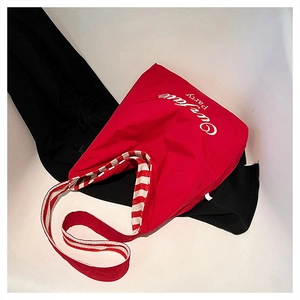 Detail of red tote bag with red and white striped straps and artistic Party print