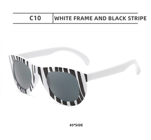 Detail of kids plastic party sunglasses featuring white frame with black stripes and grey lenses