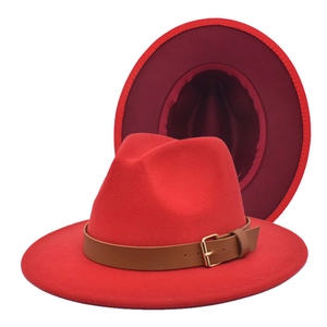 Macro shot of red wide-brim fedora hat featuring a brown faux leather buckle belt