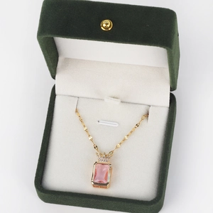 Detail of pink crystal pendant with crown motif in green velvet jewelry box