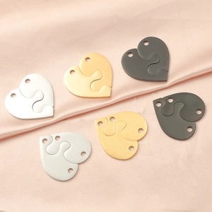 Polished heart puzzle pendants in gold, silver, and dark grey on pink silk fabric