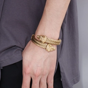 Macro detail of gold-plated double leopard head twisted cable bracelet on male wrist