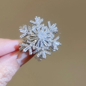 Detail shot of a silver snowflake brooch featuring white rhinestones and a geometric design